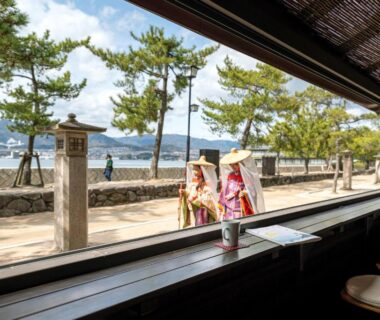 Interior counter with stools overlooking pine-lined seaside promenade, guests in kimono, Kinsuikan, Hiroshima, Chūgoku, Japan