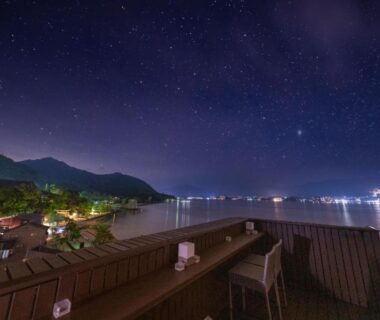 Rooftop terrace seating under starry sky overlooking illuminated bay at Kinsuikan in Hiroshima, Chūgoku, Japan