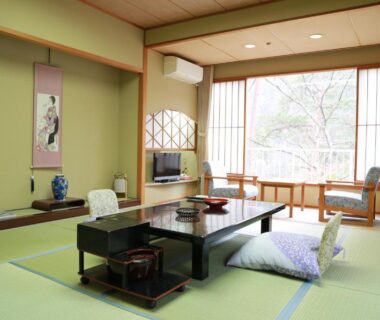 Traditional tatami room with low table, zabuton cushions, shoji screens and large window showing outdoor greenery at Matsuya Tochigi
