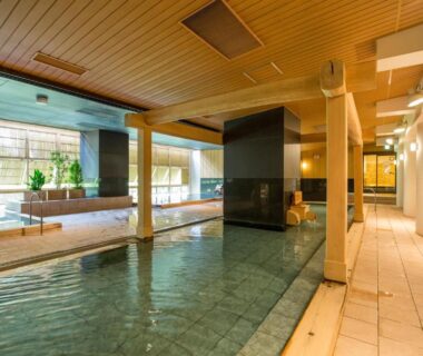 Indoor communal onsen with wooden ceiling, tiled floors and large bathing pool at Kinugawa Onsen Hotel, Tochigi