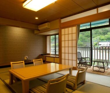 Tatami room with low table, zaisu chairs and sliding shoji doors opening to balcony at Kinugawa Onsen Hotel, Tochigi