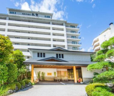 Multi-story ryokan entrance with landscaped shrubs at Kinugawa Onsen Sanraku in Tochigi, Kanto