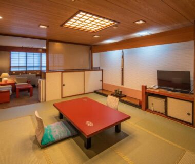 Tatami room with low table, zabuton cushions, seating area and TV at Kinugawa Park Hotels, Tochigi