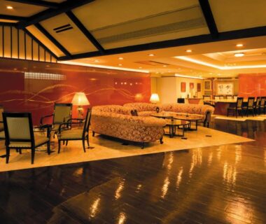 Interior lounge with sofas, armchairs, lamps and polished wooden floor at Kinugawa Park Hotels in Tochigi