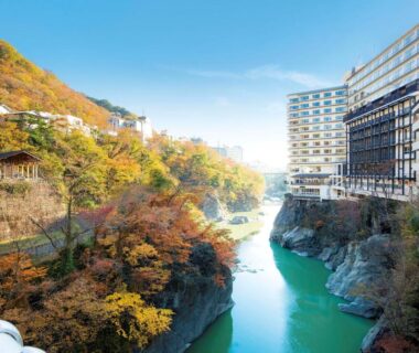 Green river winding through autumn-clad gorge beside Kinugawa Plaza Hotel in Tochigi