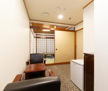 Small ryokan interior with tatami room, shoji screens, low wooden table, armchairs and compact refrigerator