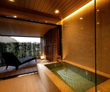 Indoor stone bath with glass wall and terrace lounge at Kinzan in Hyōgo