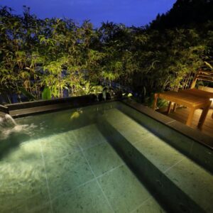 Nighttime outdoor onsen with wooden deck and bamboo backdrop at Kinzan in Hyōgo, Kansai