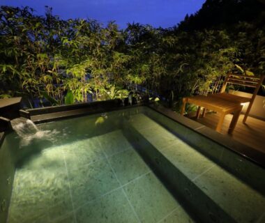 Nighttime outdoor onsen with wooden deck and bamboo backdrop at Kinzan in Hyōgo, Kansai