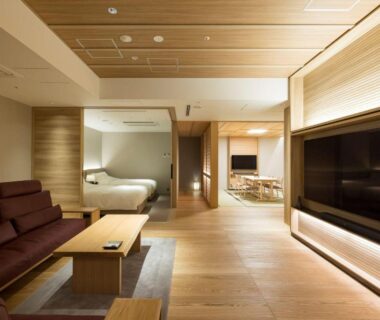 Open-plan wooden interior with sofa, low table and bed at Kinzan in Hyōgo, Kansai