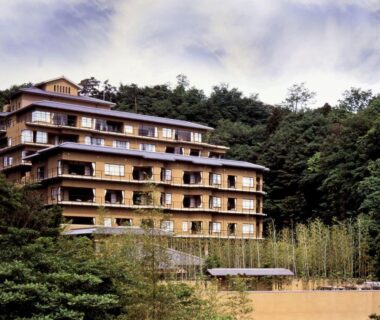 Multi-story ryokan building on wooded hillside with bamboo grove in front at Kinzan Hyōgo Kansai