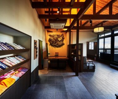 Shelves of folded yukata beside a wooden-beamed lobby at Kisara ryokan in Mie prefecture