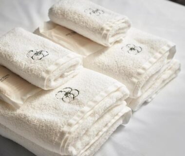 Folded white towels with embroidered crest on bed at Kisara in Mie, Kansai, Japan