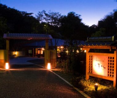 Illuminated wooden entrance sign and lit driveway leading to Kisara ryokan at dusk in Mie, Kansai