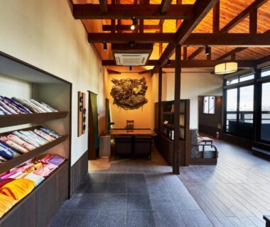 Ryokan entrance lounge with folded yukata on shelves, exposed wooden beams, seating area and large windows at Kisara in Mie