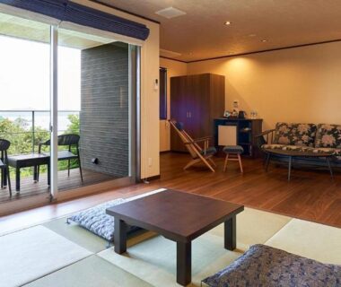 Tatami seating, low table, sofa and bed at Kisara Bettei TOKI near balcony overlooking greenery, Mie