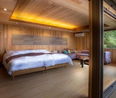 Twin beds with wooden interior and sliding glass doors opening to balcony at Kisara Oneness, Mie, Kansai