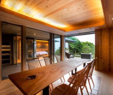 Interior dining area with long wooden table and chairs, glass doors to garden at Kisara Oneness Mie