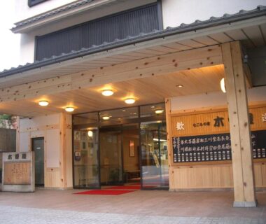 Wooden facade with glass sliding doors and lit canopy at Kisoya ryokan entrance in Gifu Chūbu
