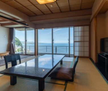 Tatami room with low table, shoji screens and sliding doors opening to sea view in Shizuoka