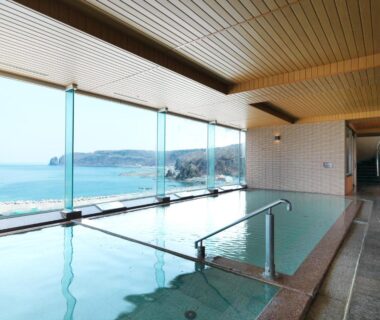 Indoor onsen bath with floor-to-ceiling windows overlooking coastline at Kitakobushi Shiretoko Hotel & Resort, Hokkaidō