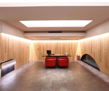 Minimal wooden lounge with two red chairs and desk, skylights and stone floor at Kitanokaze Saryo in Kanagawa