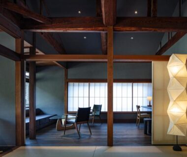 Tatami room with exposed wooden beams shoji screens low chairs and standing paper lamp at Kobayashiya Kinosaki Onsen Hyogo