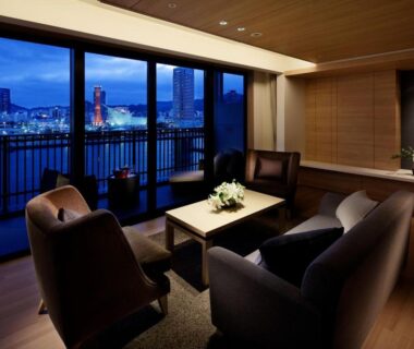 Lounge seating facing illuminated Kobe skyline through floor-to-ceiling windows at Kobe Minato Onsen Ren in Hyōgo
