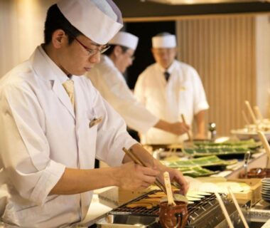 Ryokan chefs preparing grilled dishes at a live counter with plated greens at Kobe Minato Onsen Ren, Hyōgo