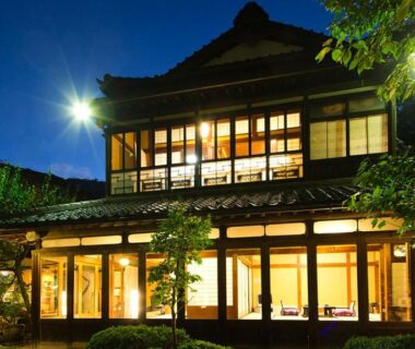 Traditional two-story ryokan lit at night with wooden facade and garden, Kocho in Ishikawa, Chūbu, Japan