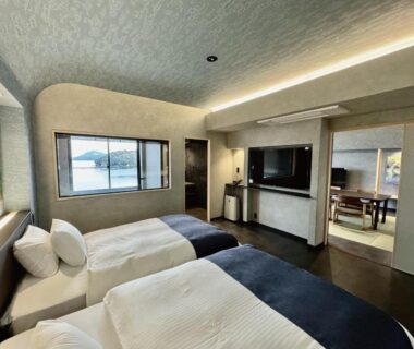Ryokan room with twin beds, low table, sliding door and window at Kochoran Mie