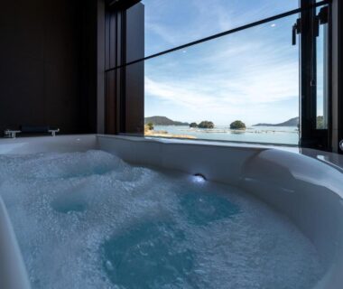 Jetted indoor bathtub beside large window overlooking coastal islands and calm sea at Kochoran in Mie