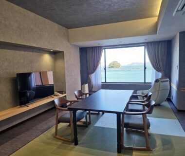 Tatami room with low table, chairs and sea view at Kochoran in Mie