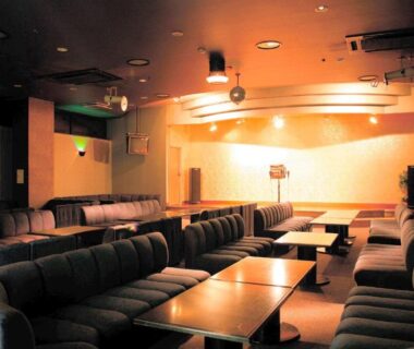 Dimly lit lounge with stage, microphone and sofa seating at Kochoran in Mie, Kansai