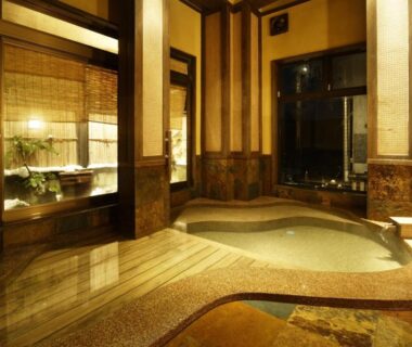 Indoor hot spring bath area with stone tubs, bamboo blinds and wooden accents at Kofukan Niigata