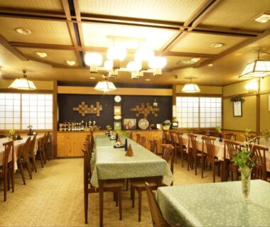 Spacious ryokan dining hall with shoji screens, set tables and warm wooden ceiling at Kofukan, Niigata