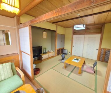 Tatami room with low table, zabuton cushions and shoji doors at Kofukan in Niigata