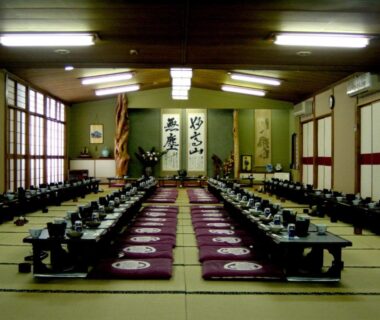 Long tatami dining room with low tables, cushions, shoji screens and calligraphy scrolls at Kofukan, Niigata