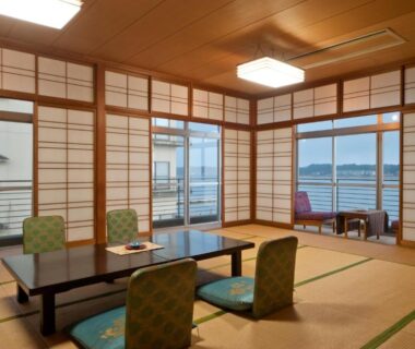 Traditional tatami room with low table, zabuton chairs, shoji screens and water view through sliding doors