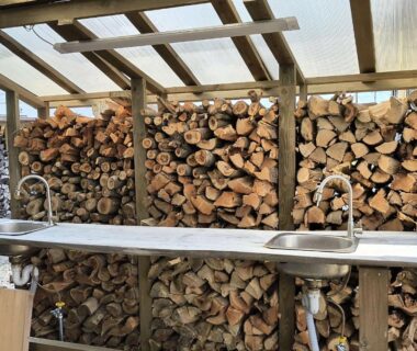Stacked firewood behind stainless steel sinks at Koinami ryokan in Mie, Kansai