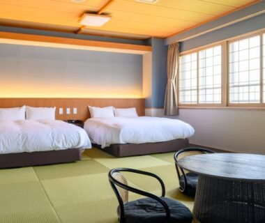 Tatami floor room with two western beds, low table and shoji windows at Kojohama Onsen Hotel, Hokkaidō