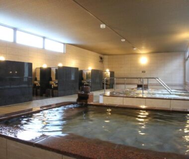 Indoor onsen pools with tiled baths and large windows at Kojohama Onsen Hotel, Hokkaidō