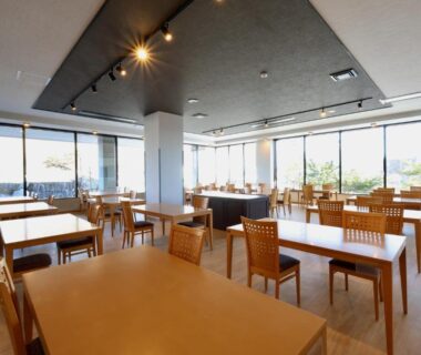 Spacious wood-furnished dining area with large windows at Kojohama Onsen Hotel in Hokkaidō