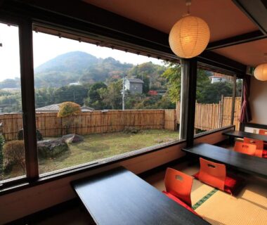 Tatami seating with low tables overlooking a garden and distant mountain at Kokoronodoka in Shizuoka