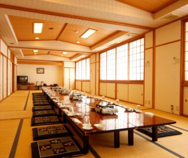 Long tatami dining hall with low tables and cushions at Komao ryokan in Nagano