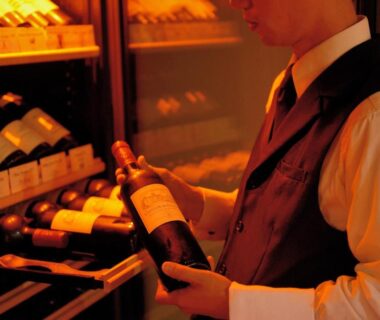 Staff choosing bottle from wooden wine rack at Komatsu-kan Kofu-tei in Miyagi, Tōhoku