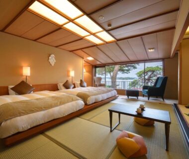Spacious tatami room with three low beds, shoji screens, low table and balcony view at Komatsu-kan Kofu-tei in Miyagi