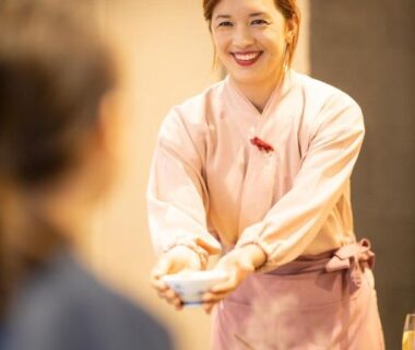 Smiling server in pink uniform presenting a meal to guest at Komatsuya Hachinobou dining room Shizuoka