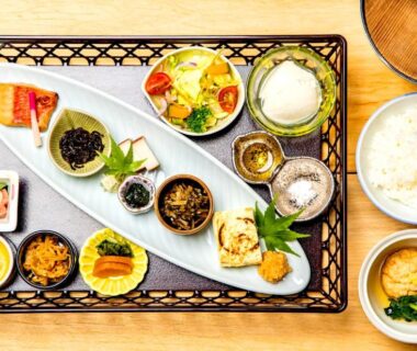 Traditional Japanese breakfast assortment with rice, miso soup and small side dishes on a woven tray