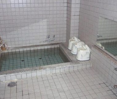 Communal tiled indoor bath with stools and mirror at Komaya Ryokan, Yamanashi